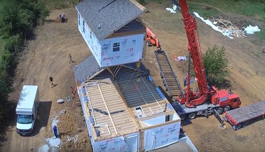 One of our modular homes assembled on site showing a crane lifting a second floor section into place.